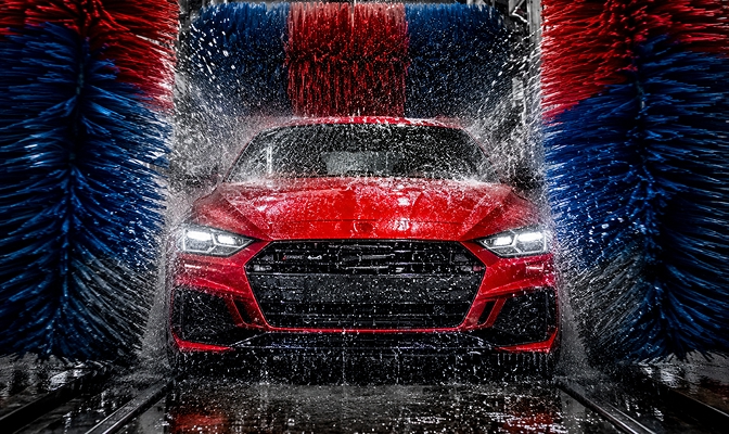 Na slici je crveni automobil u automatskoj auto-perionici tokom pranja vozila.